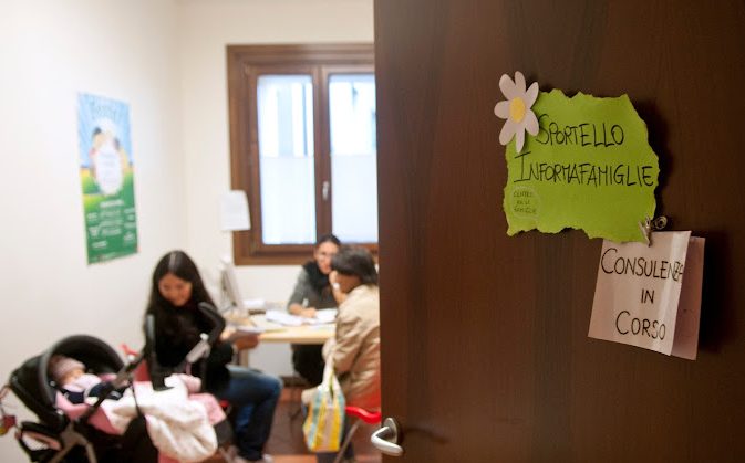 Una sala del Centro per le famiglie con una mamma con una bimba nel passeggino che sta chiedendo una consulenza alle operatrici