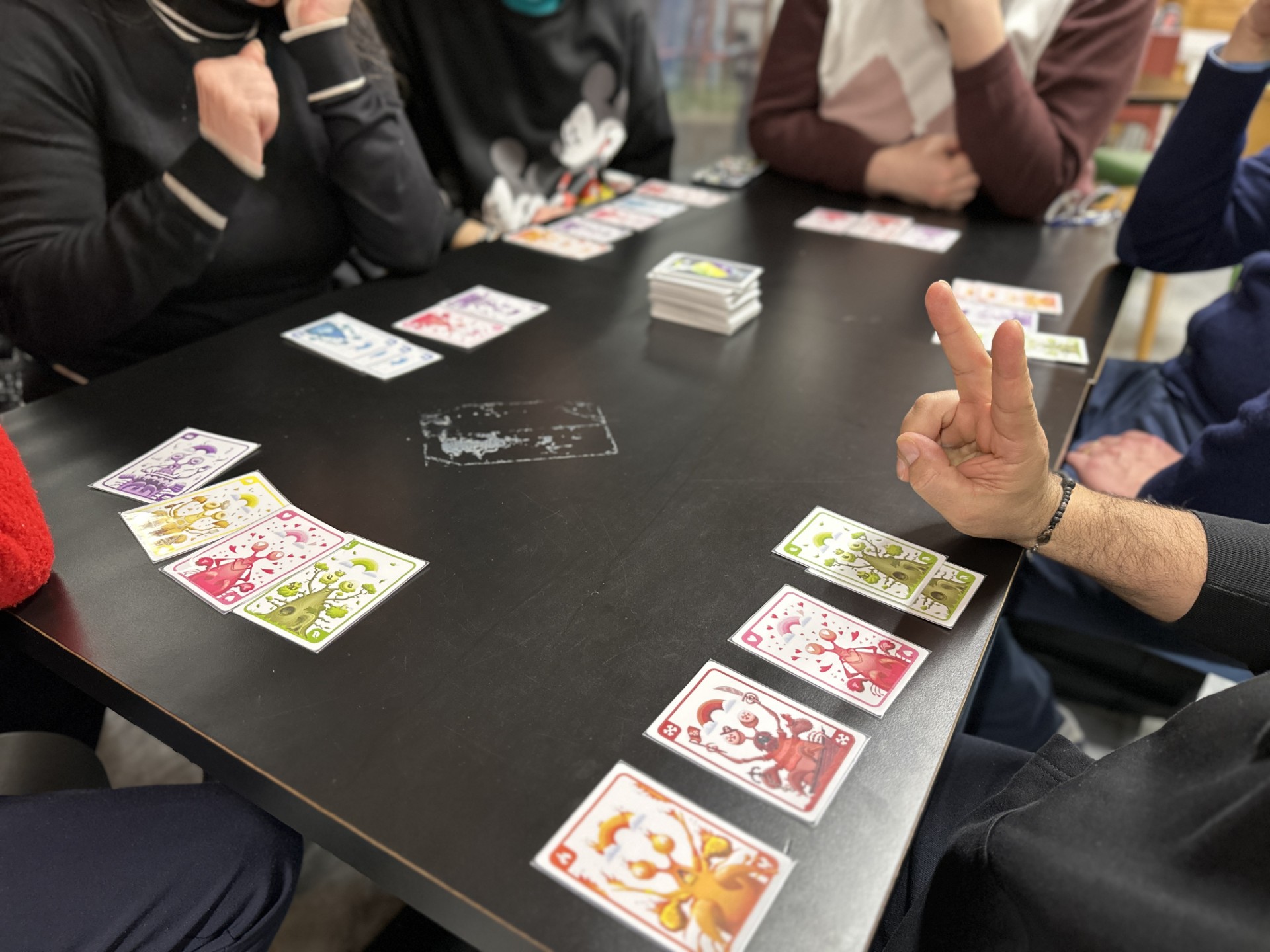 Tavolo con carte e giocatori di The Rainbow Players intorno al tavolo