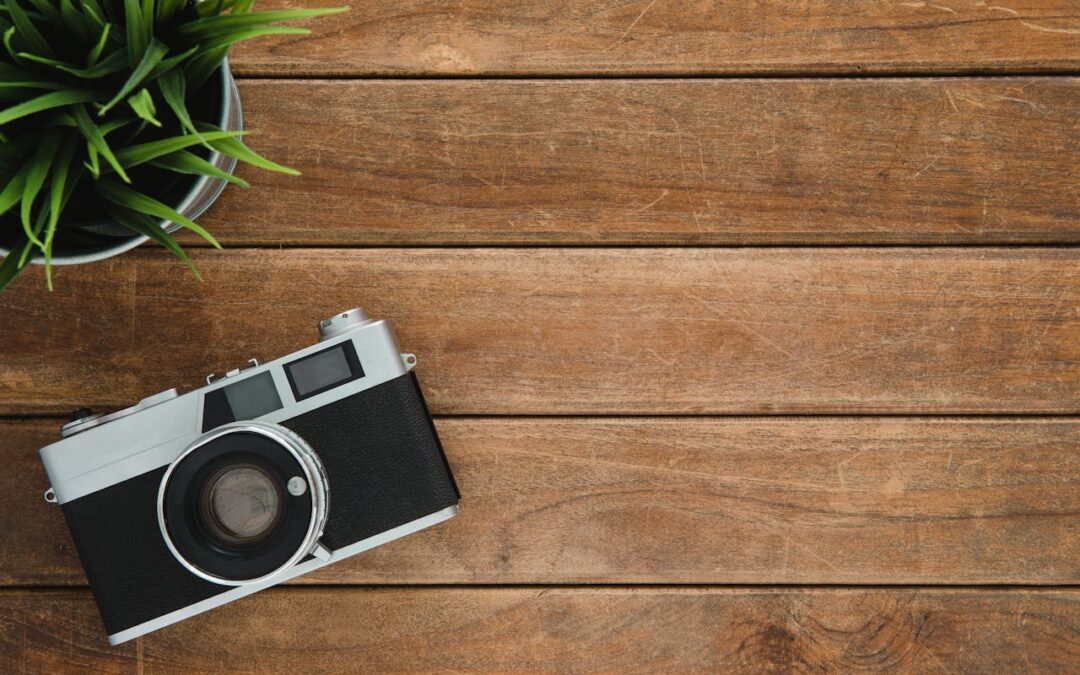 Una macchina fotografica e una pianta su un tavolo di legno