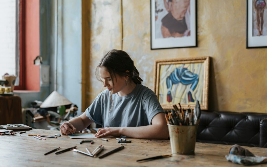 Una giovane artista al lavoro seduta a un tavolo